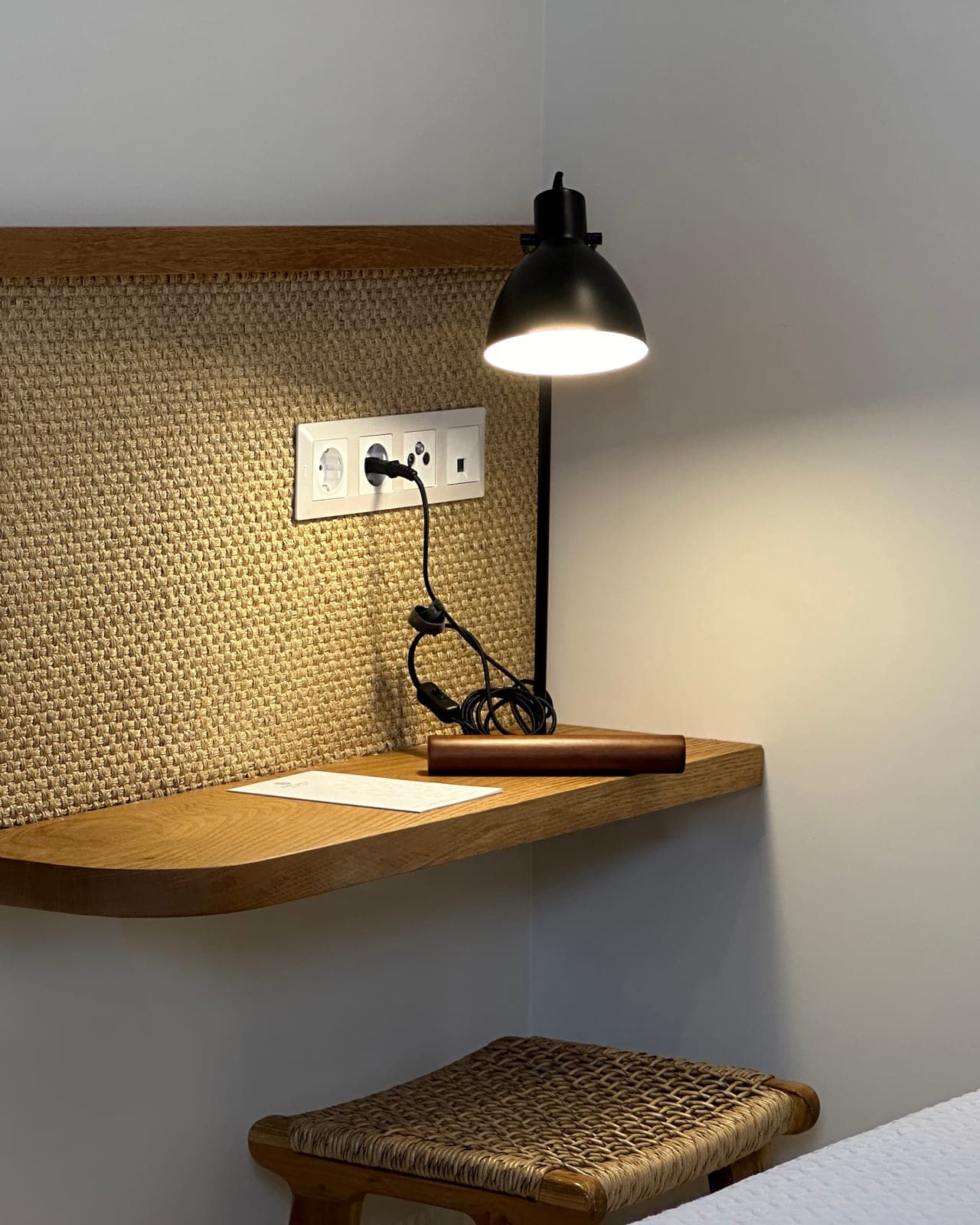 Desk lamp and oak shelf against a woven wall